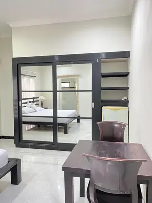 a bedroom with a bed and a table and a mirror at Kubu In Dhana Sanur Guest House in Mantaak