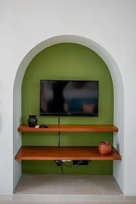 a flat screen tv sitting on top of a green wall at Tropical 3BR Oasis w Private Pool Villa Nau Mai in Seminyak