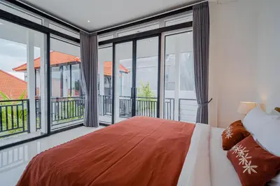 a bedroom with a large bed and large windows at Villa Orchid Heaven by Bali Villa Solutions in Seminyak