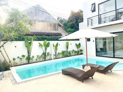 a swimming pool with an umbrella and two chairs and a table and an umbrella at Dakings Greece House in Legian