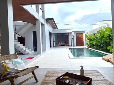 a villa with a swimming pool and a chair at Rumah Melissa - Modern Boho 3BR Brand New Villa in Sanur in Sanur