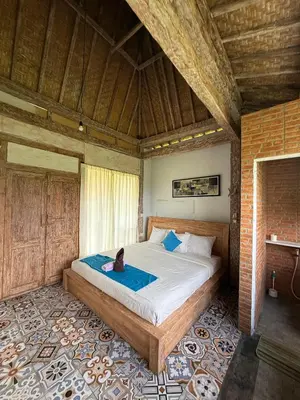 a person sitting on a bed in a room at Balian Retreat Centre Homestay in Sanur