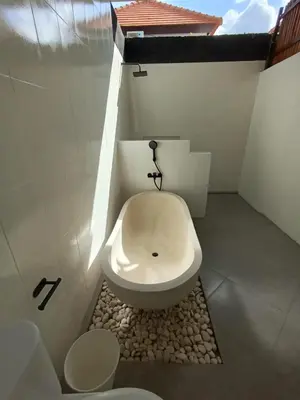 a bathroom with a toilet in the corner of a room at Villa Bu H in Kerobokan