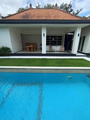 a house with a swimming pool in front of a house at Villa Bu H in Kerobokan