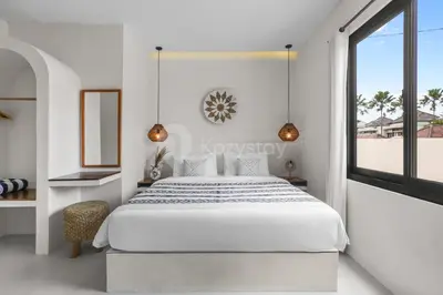 a white bedroom with a large bed and a window at Kirelo Villa by Kozystay - Sanur in Sanur