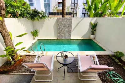 a swimming pool with two chairs and a table and a pool at Domaxo Villa in Seminyak