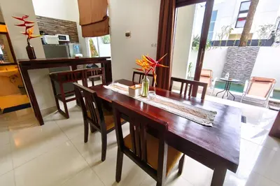 a dining room with a wooden table and chairs at Domaxo Villa in Seminyak