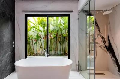 a bath tub in a bathroom with a window at Anoya Boutique Villa in Kerobokan