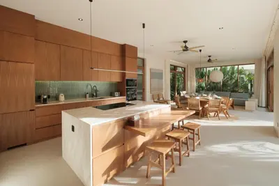 a kitchen with wooden cabinets and a table and chairs at Manu Villas in Sanur