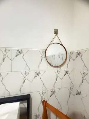a mirror hanging on a white tiled wall at Private Room Near Sanur Beach Bali in Sanur