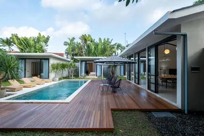 a house with a wooden deck and a swimming pool at Villa Seminyak Beachside Luxury in Seminyak