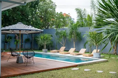 a swimming pool with chairs and an umbrella and a table and chairs sidx sidx sidx at Villa Seminyak Beachside Luxury in Seminyak
