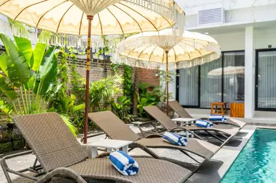 a group of chairs and umbrellas next to a pool at Uma Katani in Jimbaran