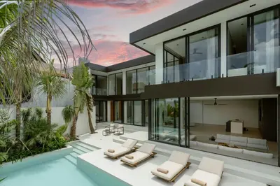 an exterior view of a house with lounge chairs at Ultra-Luxe 4BR Seminyak Villa - Indoor AC Living & Private Pool in Seminyak