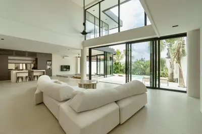 a living room with a white couch and a kitchen at Ultra-Luxe 4BR Seminyak Villa - Indoor AC Living & Private Pool in Seminyak