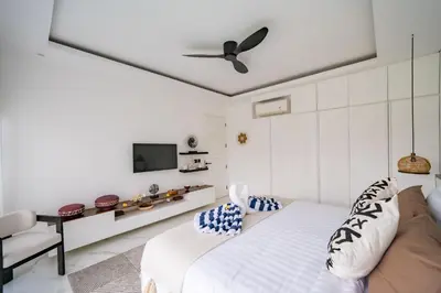 a white bedroom with a bed and a tv at Villa Samyati Kerobokan in Seminyak