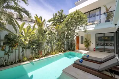 a swimming pool in front of a house with plants at Villa Samyati Kerobokan in Seminyak