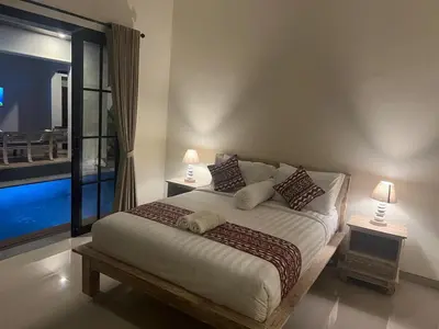 a bedroom with a large bed with two lamps at FrangipaniVilla in Seminyak