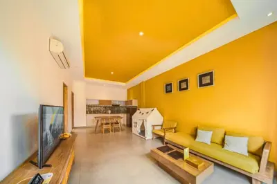 a living room with a yellow wall and a couch at Teagan Pretty 1 BR Royal Private Pool Villa With Waterslide in Kerobokan