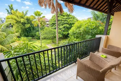 a balcony with chairs and a view of the jungle at Palm 57 Guest House Legian in Legian