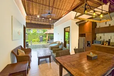 a kitchen and living room with a wooden table at Malayna Comfortable 2 BR Royal Private Pool Villa in Seminyak