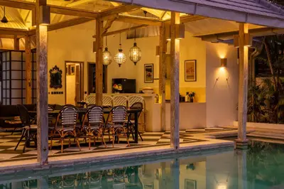 a patio with a table and chairs next to a swimming pool at Luxe Bali Seminyak Villa by Betterplace in Seminyak