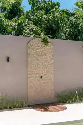 a white fence with a stone wall with plants at Villa Batu, Superb 4BR beachside in Canggu