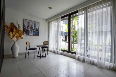 a living room with a table and chairs and a large window at Norm Villa Kuta in Kuta