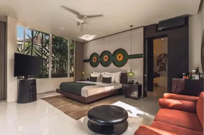 a bedroom with a bed and a couch and a ceiling fan at Chaesa Comfortable 1 BR Royal Private Pool Villa in Kerobokan