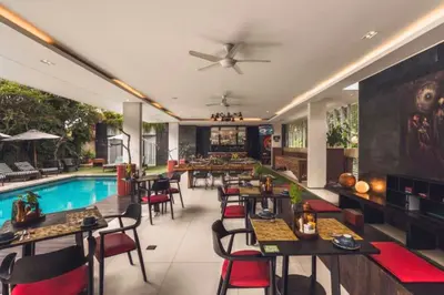 a restaurant with a pool and tables and chairs at Varnika Peaceful 1 BR Suite Double Room in Kerobokan