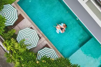 an overhead view of a person swimming in a pool with umbrellas at Varnika Peaceful 1 BR Suite Double Room in Kerobokan