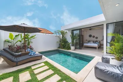 a swimming pool with an umbrella next to a house at 3BRVilla Minutes from Seminyak, Petitenget, Canggu in Kerobokan