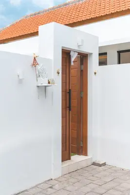 a white house with a brown wooden door at 3BRVilla Minutes from Seminyak, Petitenget, Canggu in Kerobokan