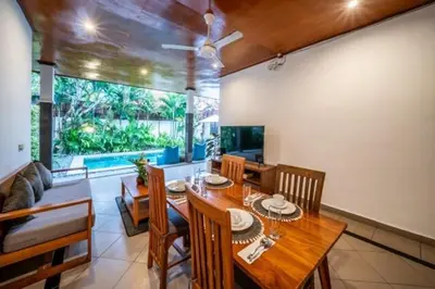 a dining room with a wooden table and chairs at Prime Seminyak 2BR Villas in Seminyak