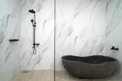 a bath tub in a bathroom with a marble wall at Coastal Bliss Private 2BR Pool Villa Jimbaran in Jimbaran