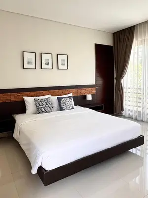 a bedroom with a large white bed with three pictures on the wall at Villa Hale Mahina, Bali in Kerobokan