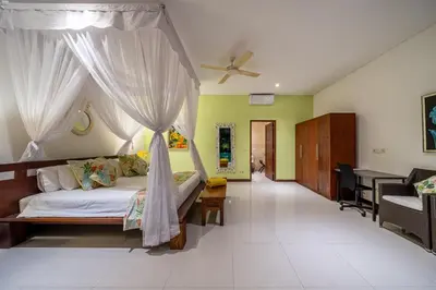 a bedroom with a bed with curtains and a desk at Villa Rajawali 3BR Private Villa Near Beach in Canggu