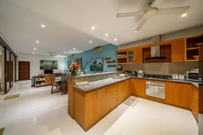 a large kitchen with wooden cabinets and a large island at Villa Samsara 3BR Pool Villa Near Berawa Beach in Canggu