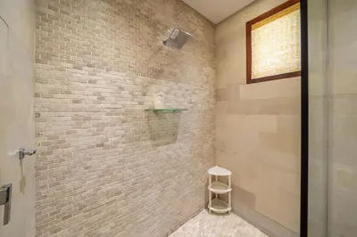 a bathroom with a shower with a stool in it at Villa Samsara 3BR Pool Villa Near Berawa Beach in Canggu