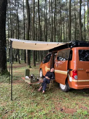 a man sitting in a chair in front of a van at Wandervan - Bali Campervan Rental in Kuta