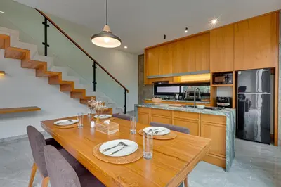 a dining room with a wooden table and a kitchen at Elegant Villa Vibhava 2BR in Central Umalas in Kerobokan