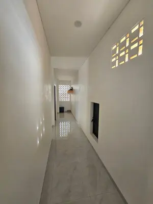 a long hallway with white walls and a window at Kubu Semangka in Sanur