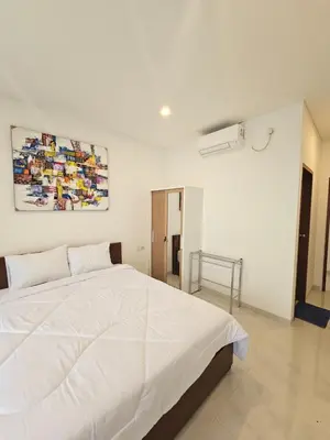 a bedroom with a white bed with a painting on the wall at Kubu Semangka in Sanur