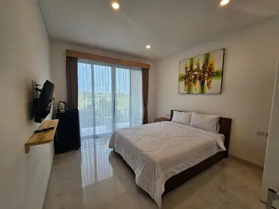 a bedroom with a bed and a large window at Kubu Semangka in Sanur