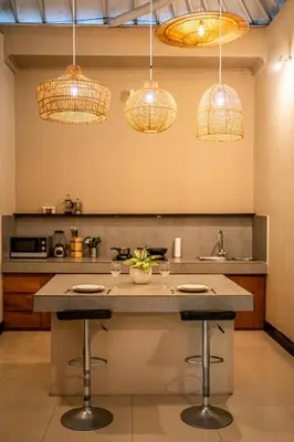 a kitchen with two bar stools and pendant lights at Villa Aditya Seminyak in Seminyak