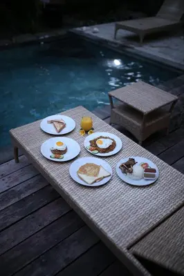 a table with plates of food on it next to a pool at Kundalini Shakta Yoga Meditasi in Denpasar