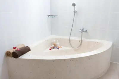 a bath tub with a shower in a bathroom at Cozy 2br villa at the beach in Canggu