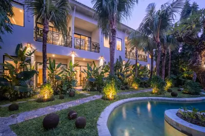 an exterior view of a house with a swimming pool and palm trees at Anam Mani New Room Central Seminyak in Seminyak
