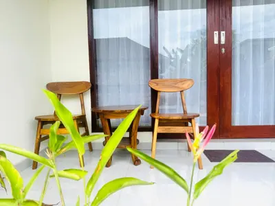 two chairs on a porch next to a door at Umah Anami in Denpasar