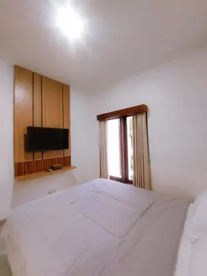 a bedroom with a white bed and a television at Villa Morich in Jimbaran